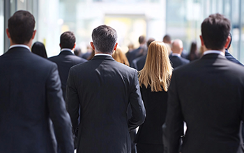 Rear view of a group of business people walking in front of a modern office building