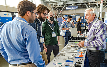 Attendees  gathered around a table filled with various tools and items, engaged in a collaborative activity